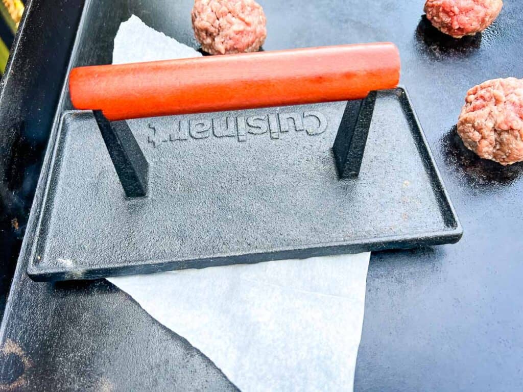 Pressing down the meat ball to make a smash burger.