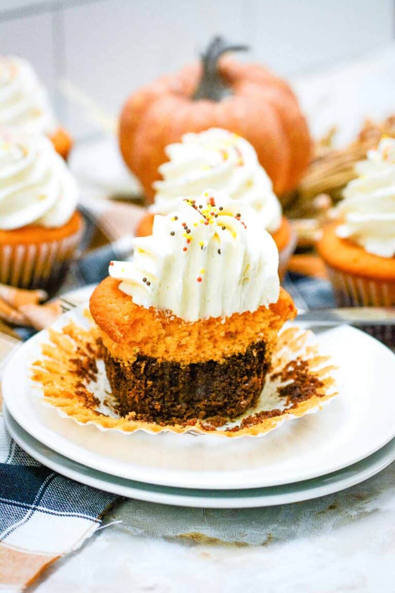 Pumpkin cupcakes on a plate with whipped cream.