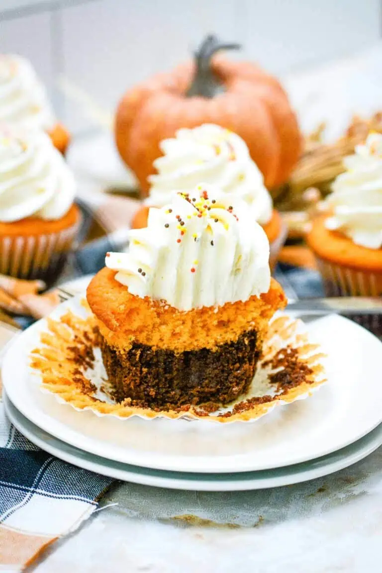 Pumpkin cupcakes on a plate with whipped cream.