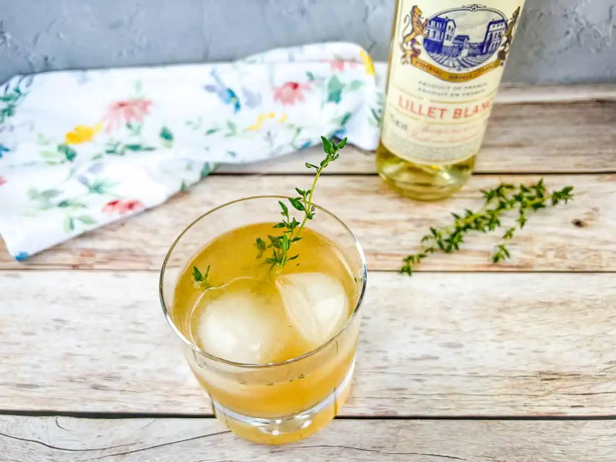 A glass with ice and a bottle of Lillet Blanc.