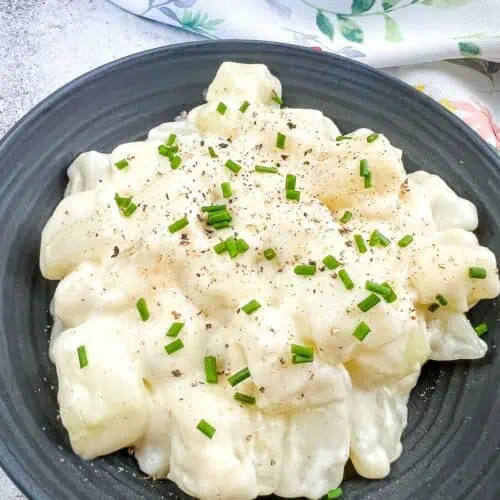 Kohlrabi in Cream Sauce on a black plate.