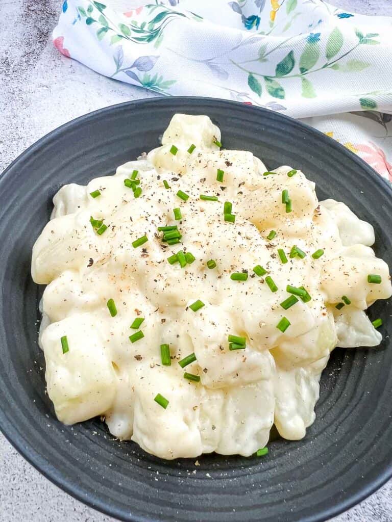 Kohlrabi in Cream Sauce on a black plate.