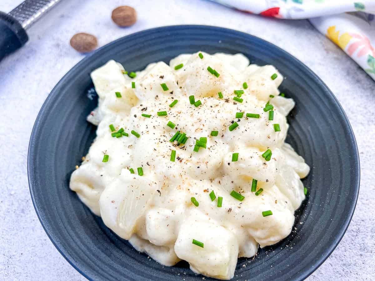 German Kohlrabi in Cream Sauce on a black plate.