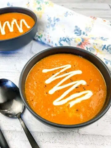 Smoked Tomato Soup with Mascarpone in a black bowl with another bowl in the background.