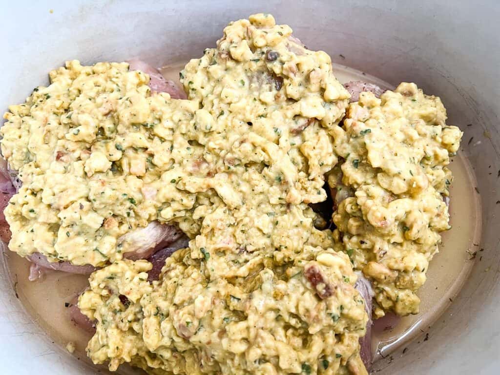 Chicken breasts in the slow cooker topped with the stuffing mixture.