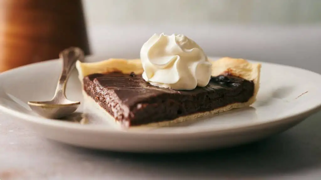 A slice of chocolate pie with whipped cream on a plate.