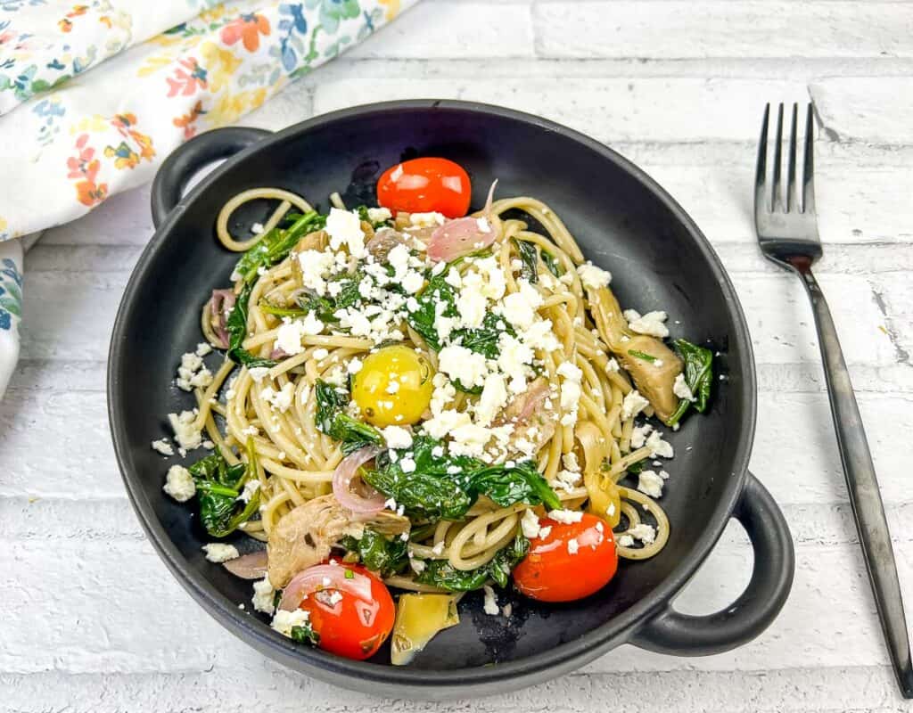 A top-down shot of Greek Spaghetti in a black bowl.