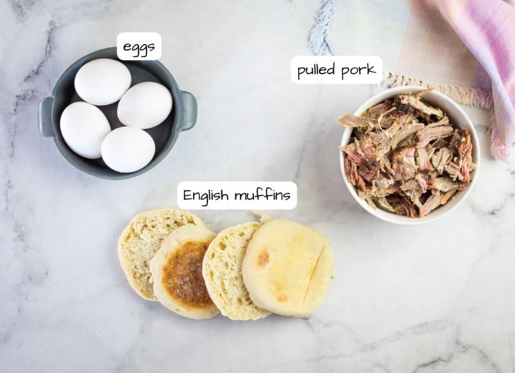The ingredients for a pulled pork eggs benedict are shown on a marble table.