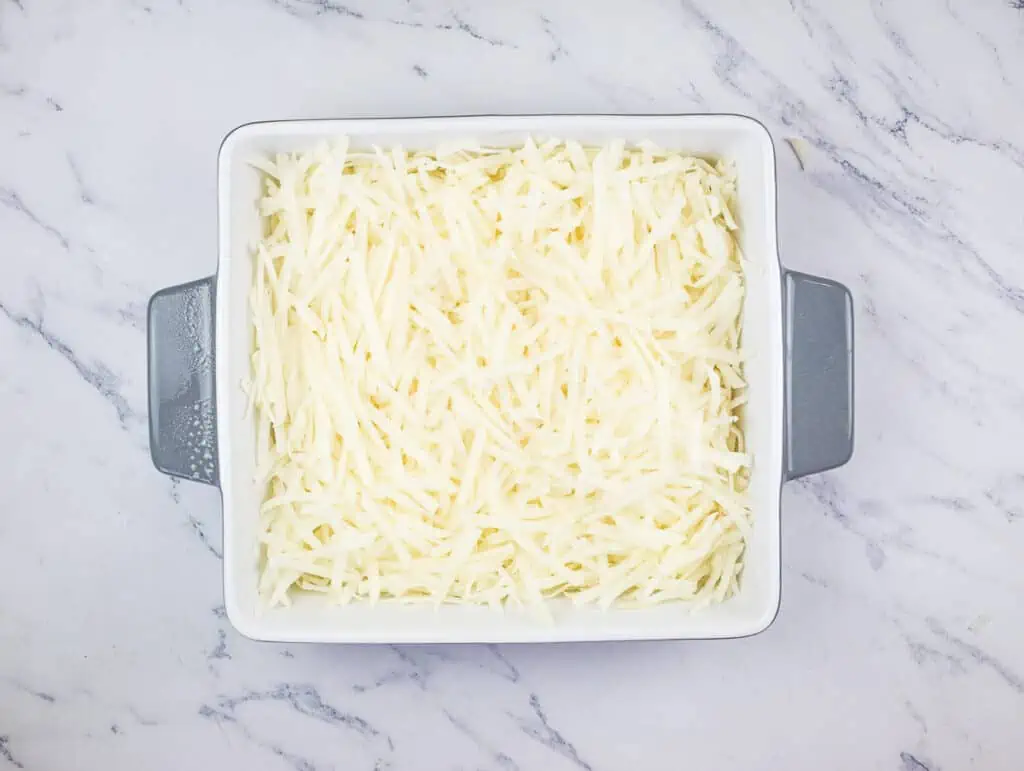 Shredded potatoes in a square baking dish.