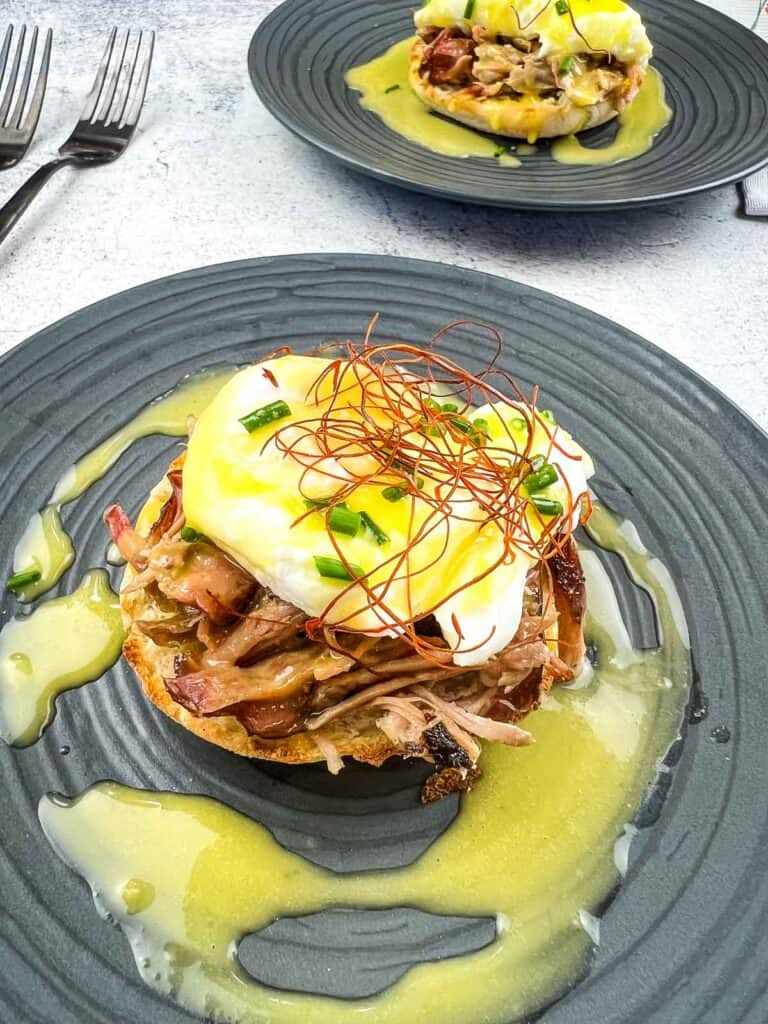 Pulled Pork Eggs Benedict on a plate with hollandaise sauce.