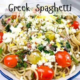 A plate of greek spaghetti with tomatoes and feta cheese.