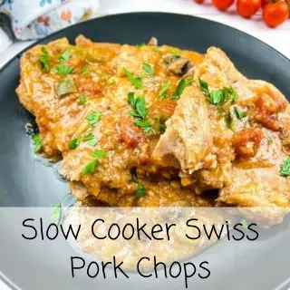 Slow cooker swiss pork chops on a black plate.