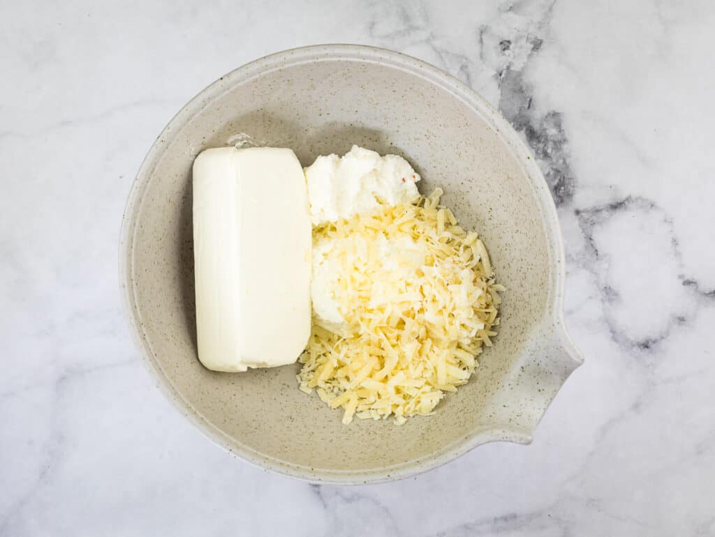 A bowl with cream cheese, parmesan cheese, and ricotta.