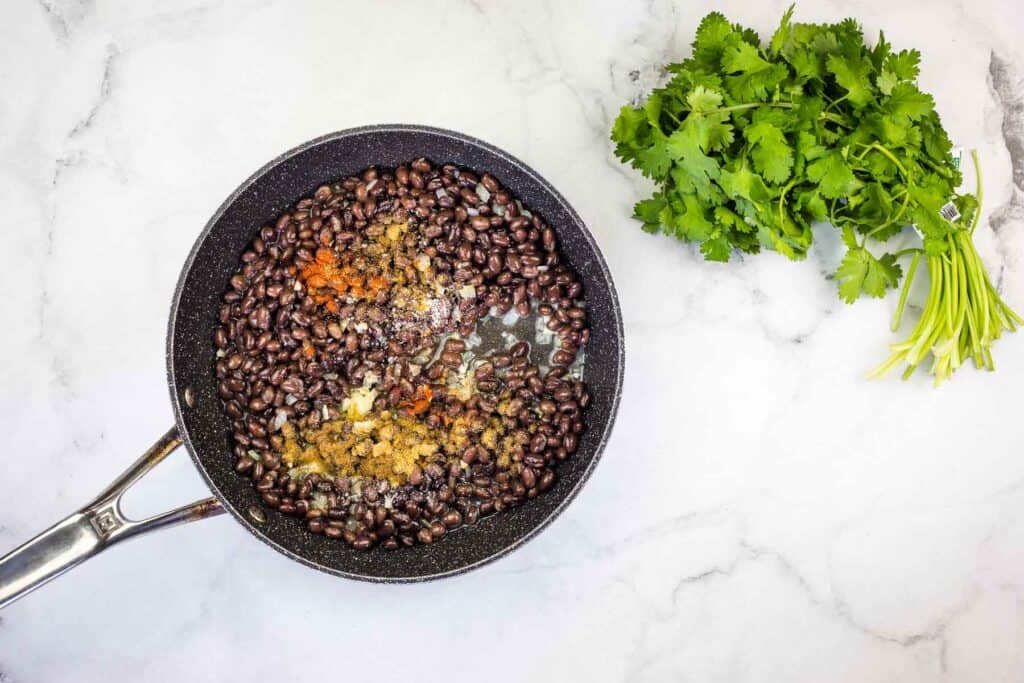 Black beans in a frying pan with parsley.