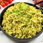 Green rice in a skillet with tomatoes and herbs.