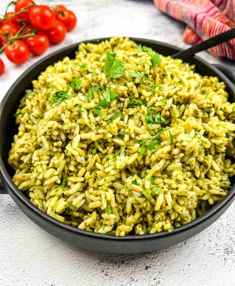 Green rice in a skillet with tomatoes and herbs.