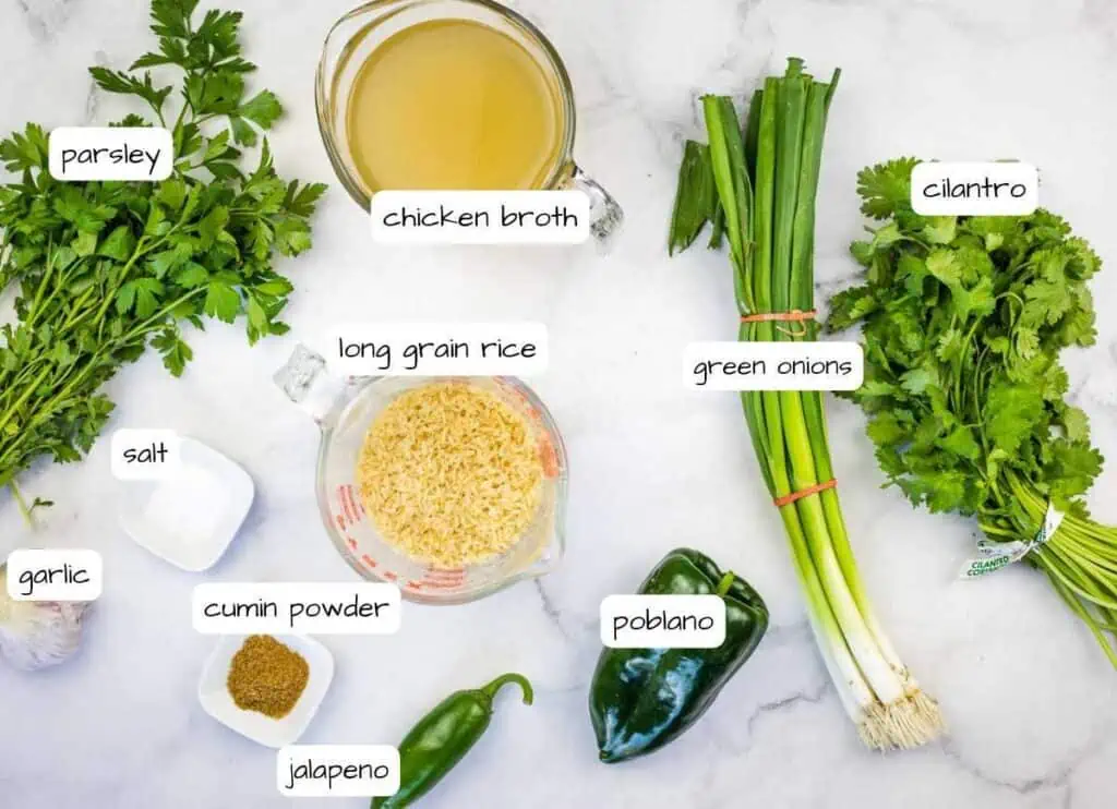 The ingredients for a chicken fried rice recipe are laid out on a marble table, featuring arroz verde.