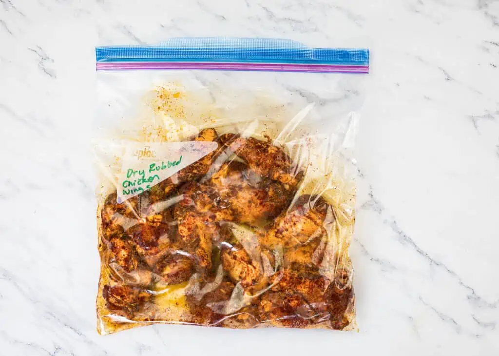 Chicken wings in a plastic bag on a marble countertop.