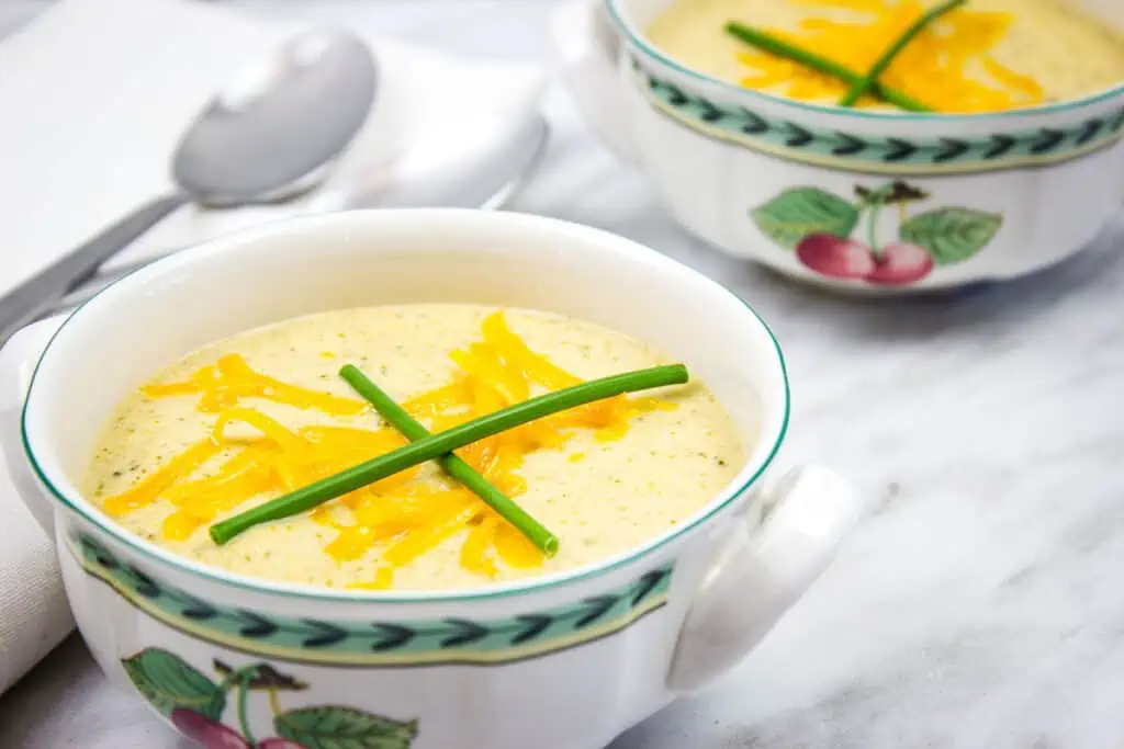 Two bowls of soup with cheese and chives.