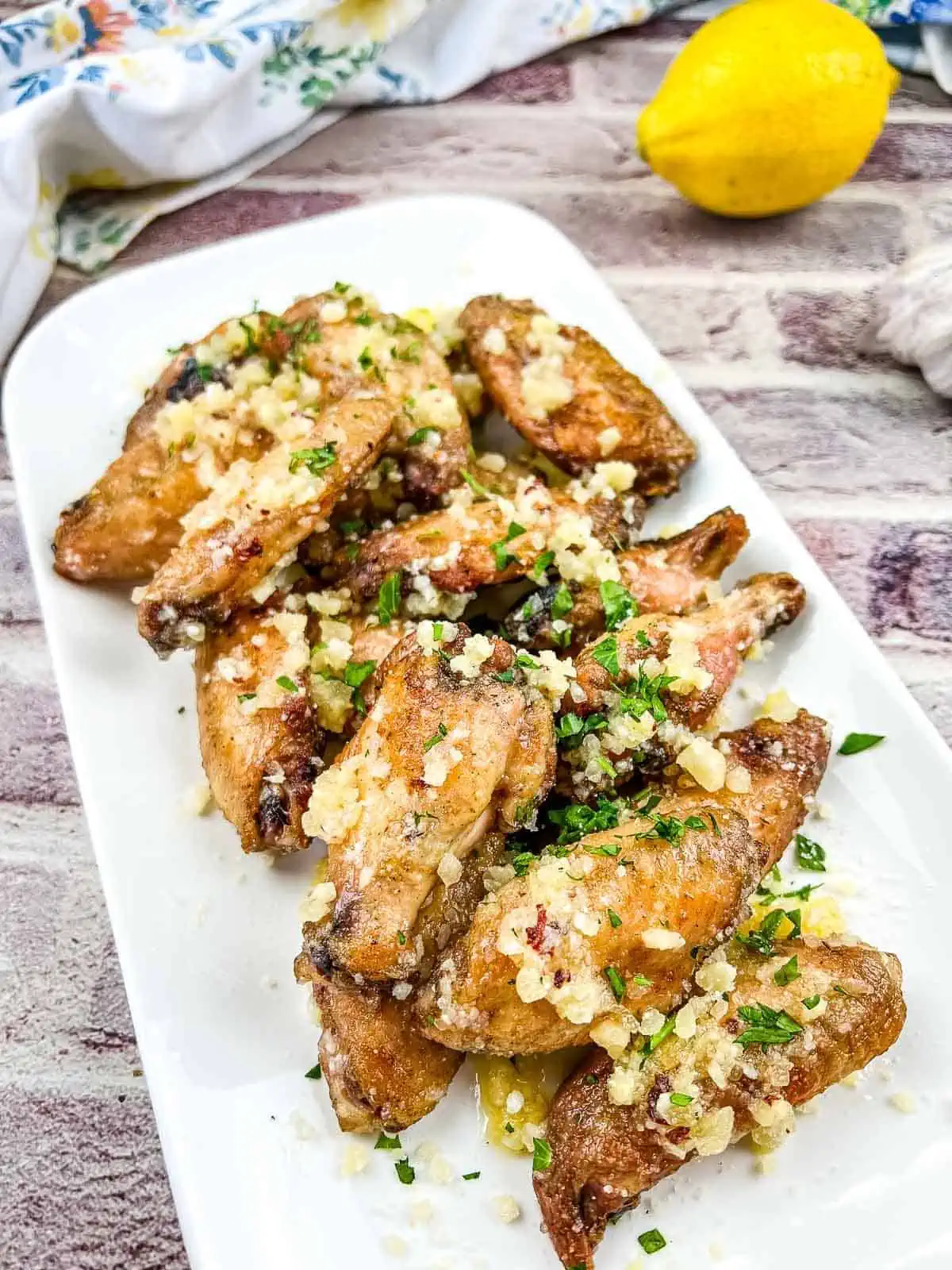 Chicken wings with lemon and garlic on a white plate.