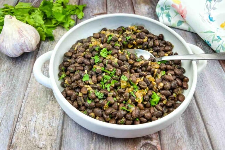 Black beans in a white bowl on a wooden table.