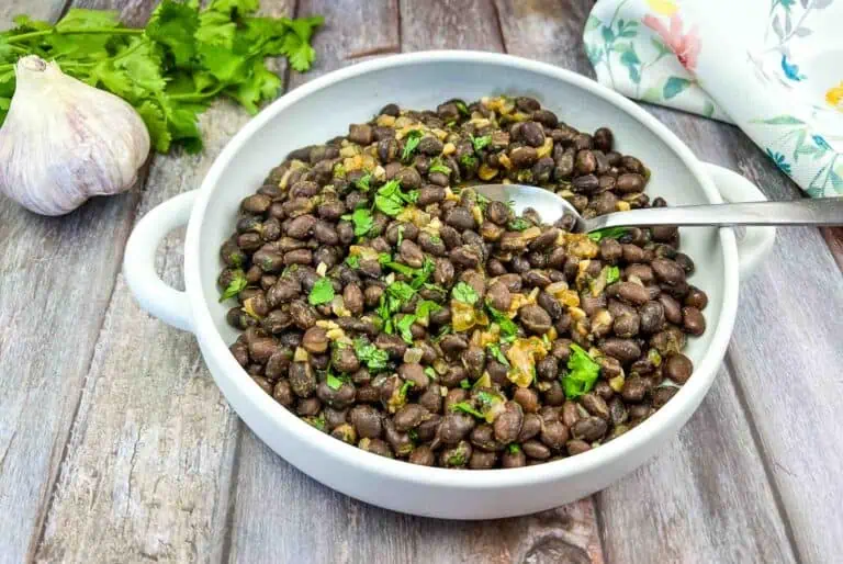 Black beans in a white bowl on a wooden table.