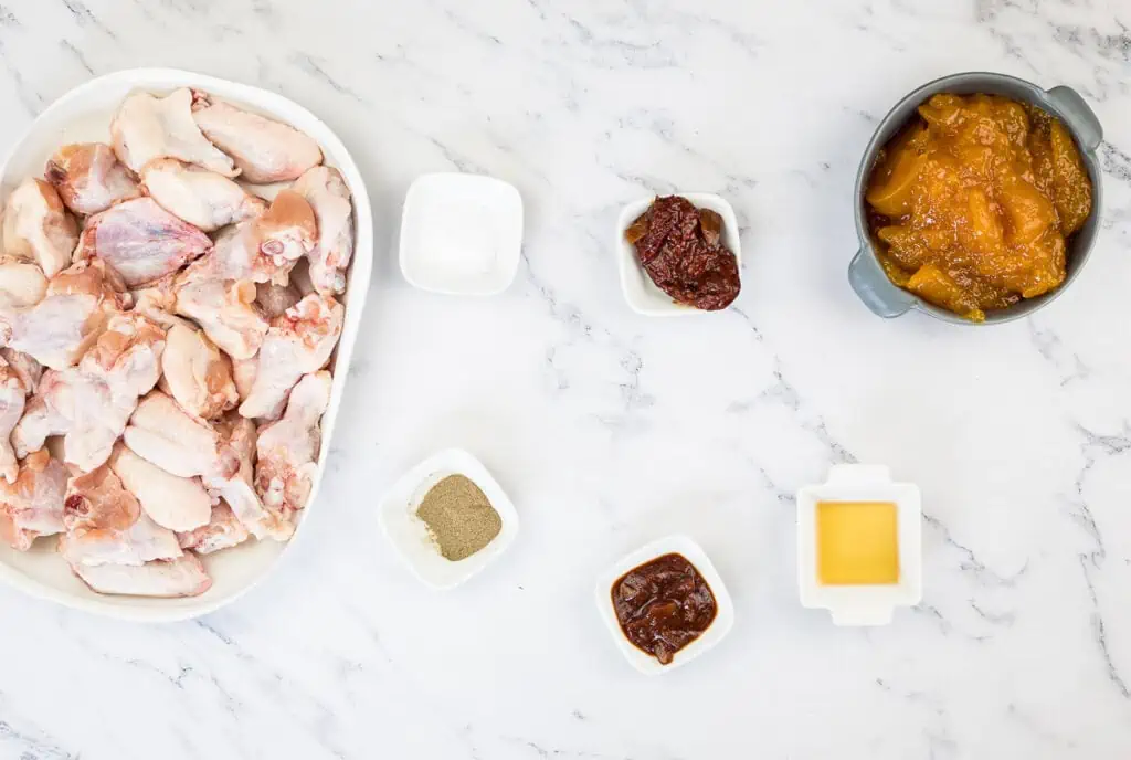 The ingredients for Smoked Peach-Chipotle Wings are laid out on a marble table.