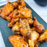 Chicken wings on a plate with sauce on the side.