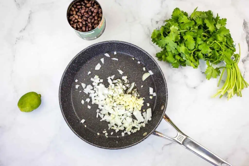 Ingredients in a frying pan on a marble countertop.