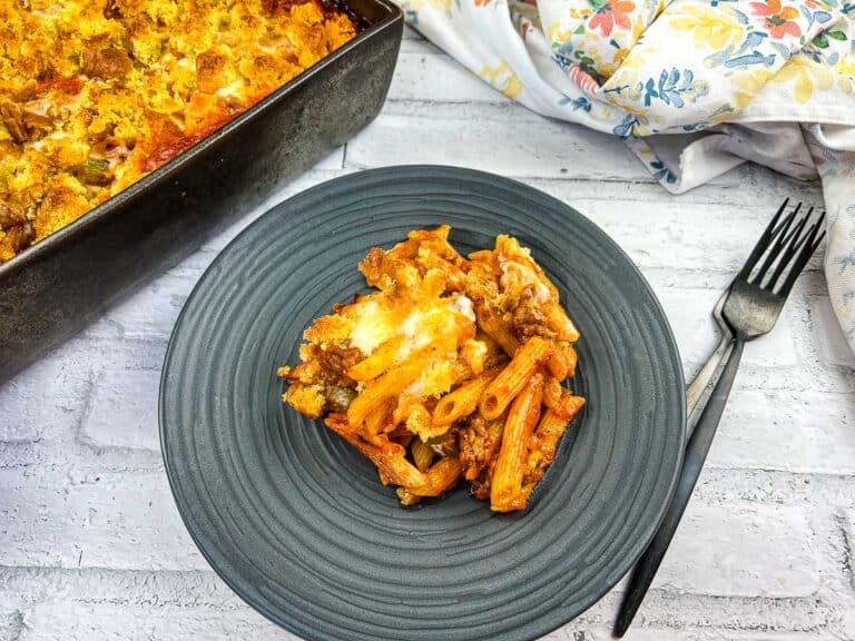 A Dish of Pasta with Meat and Cheese on a Plate next to a Fork.