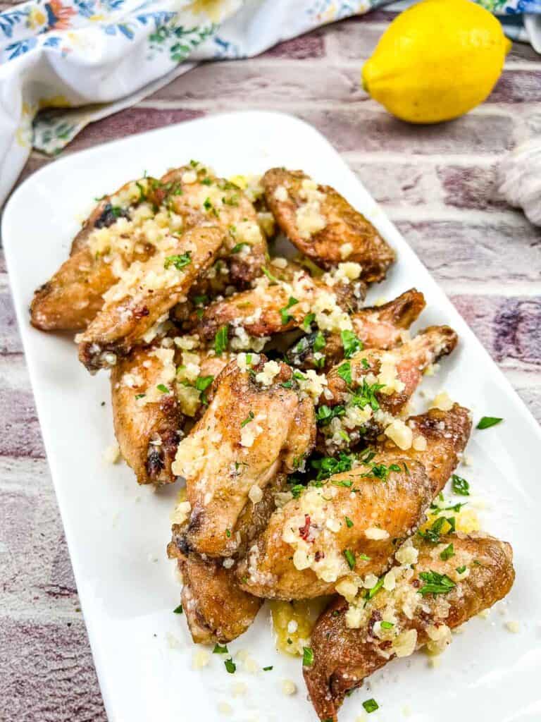Chicken wings with garlic and parsley on a white plate.