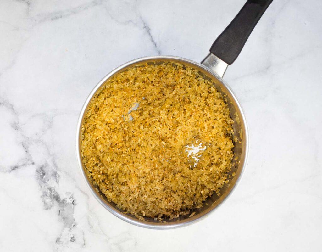 Toasted rice in a pan with a spatula.