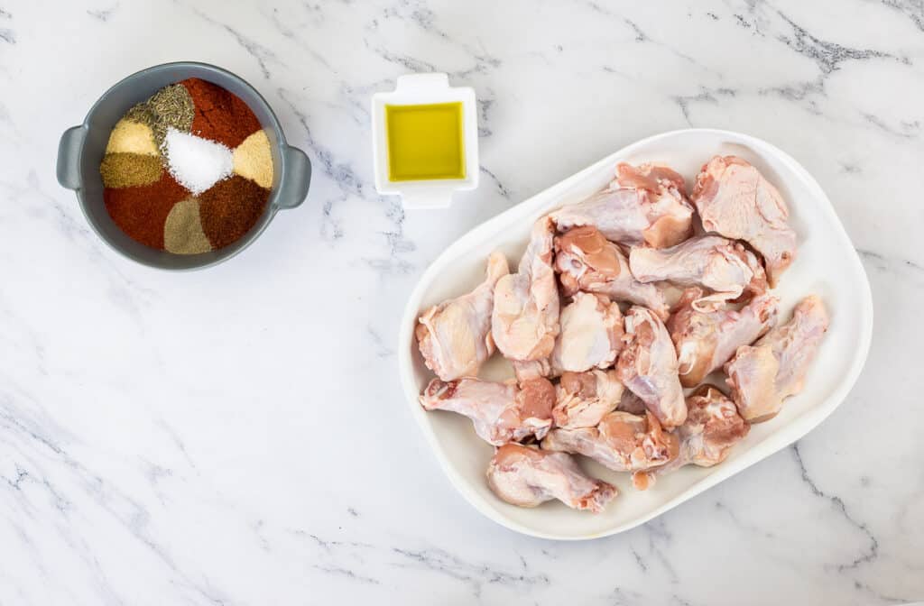 Chicken wings in a bowl with spices and seasonings.