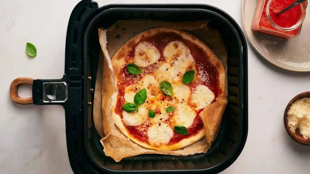 A pizza is being cooked in an air fryer.