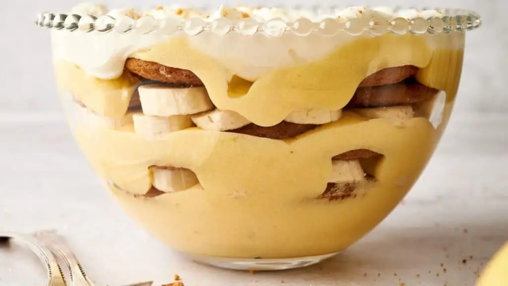 Banana trifle in a bowl with whipped cream and bananas.
