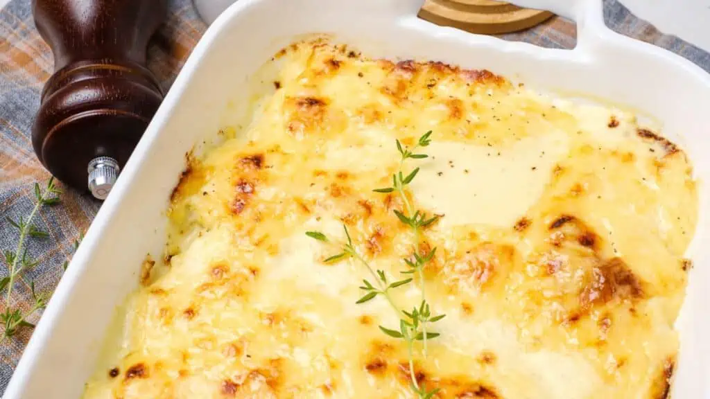 A dish of cheesy gratin with sprigs of thyme.