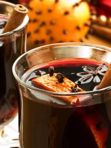 Two glasses of mulled wine with cinnamon sticks.