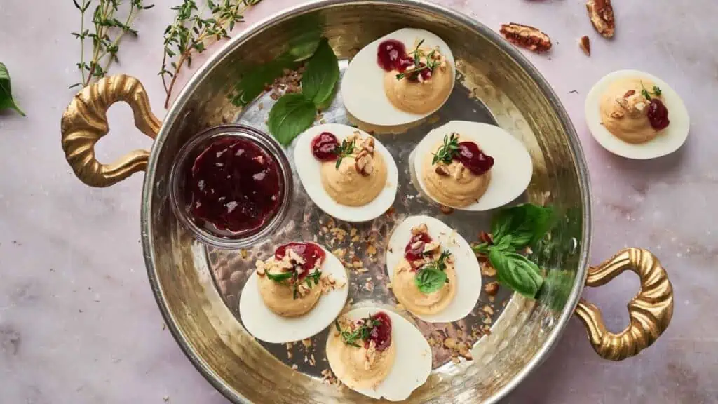 Deviled eggs with cranberry sauce on a platter.