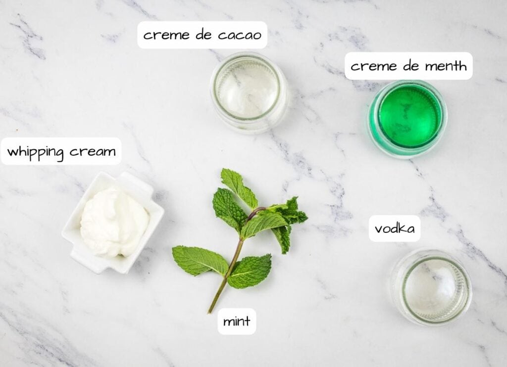 The ingredients for a mint cream are shown on a marble table.