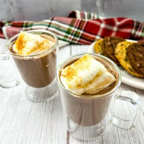 Two glasses of hot chocolate with marshmallows on top.