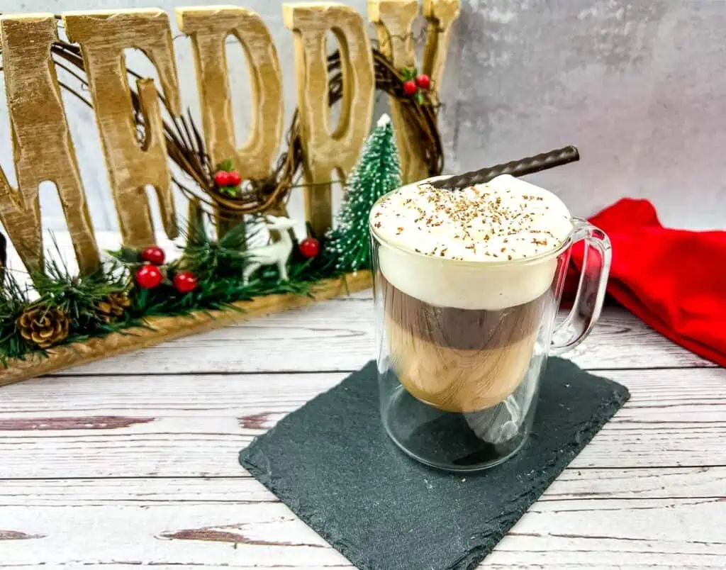 A cup of coffee with whipped cream and a christmas sign.
