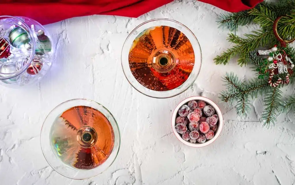 Two Cranberry Cosmosas in martini glasses of wine and berries on a white background.