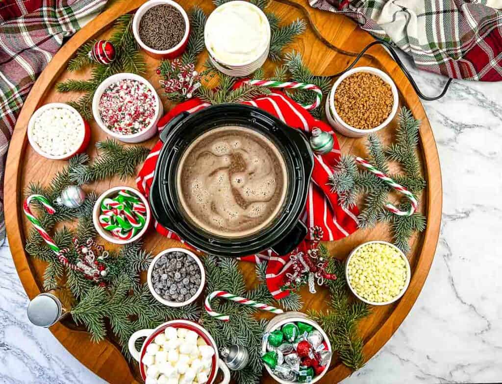 A tray of hot cocoa, marshmallows and candy on a table.