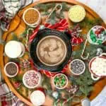 A table with hot cocoa, marshmallows, and candy on it.