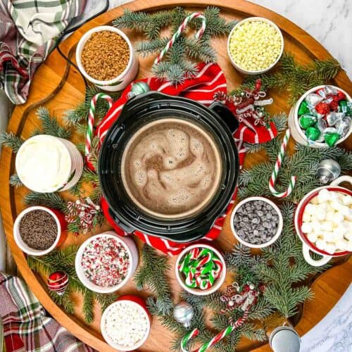 A table with hot cocoa, marshmallows, and candy on it.