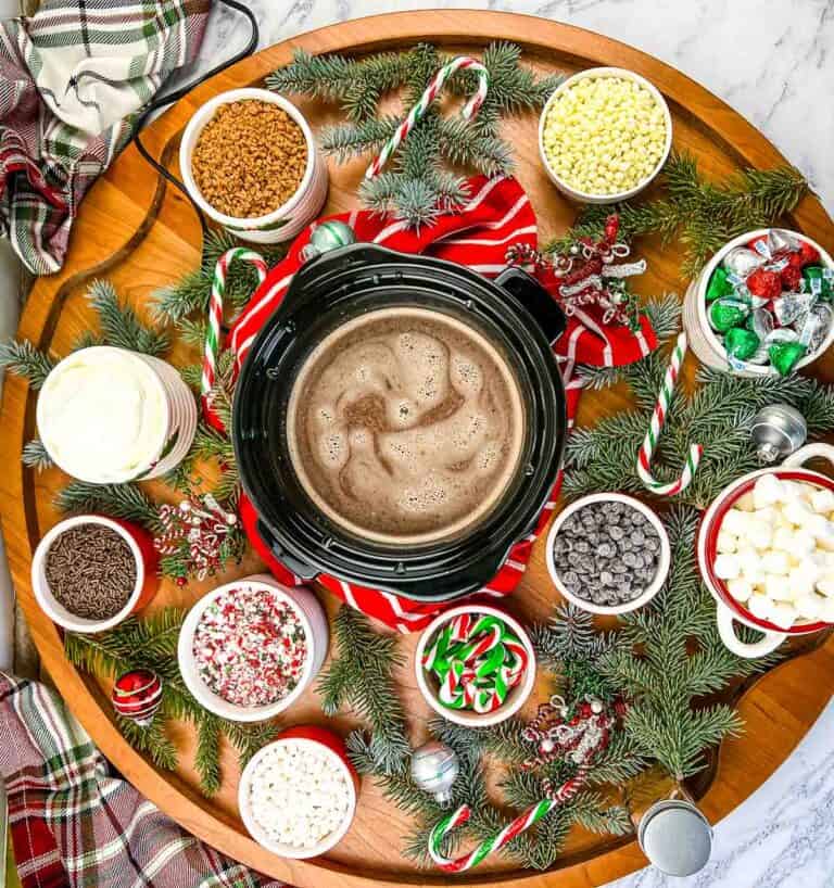 A table with hot cocoa, marshmallows, and candy on it.