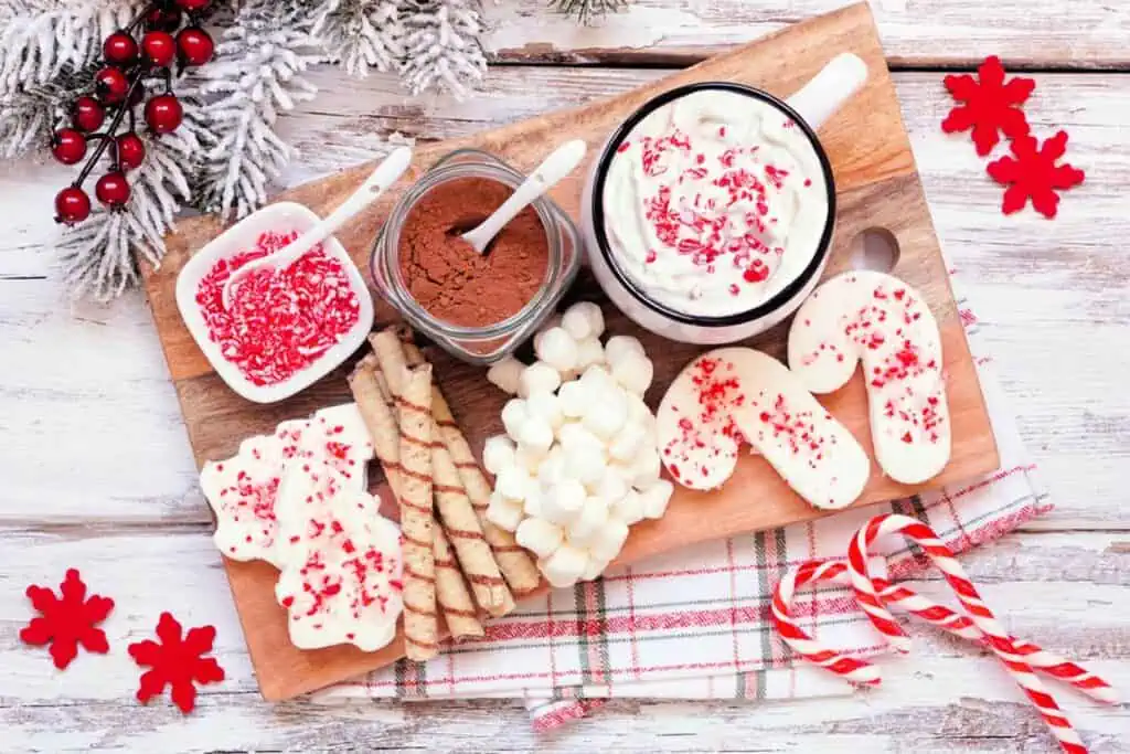 A wooden cutting board with cookies and candy on it.