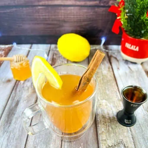 A cup of tea with lemon and cinnamon on a wooden table.