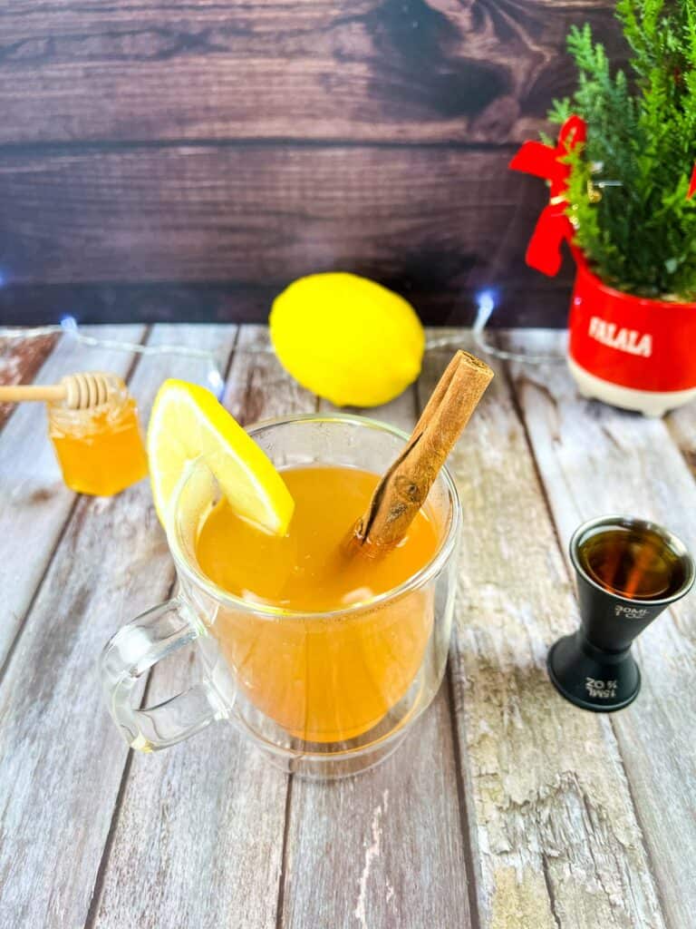 A cup of tea with lemon and cinnamon on a wooden table.
