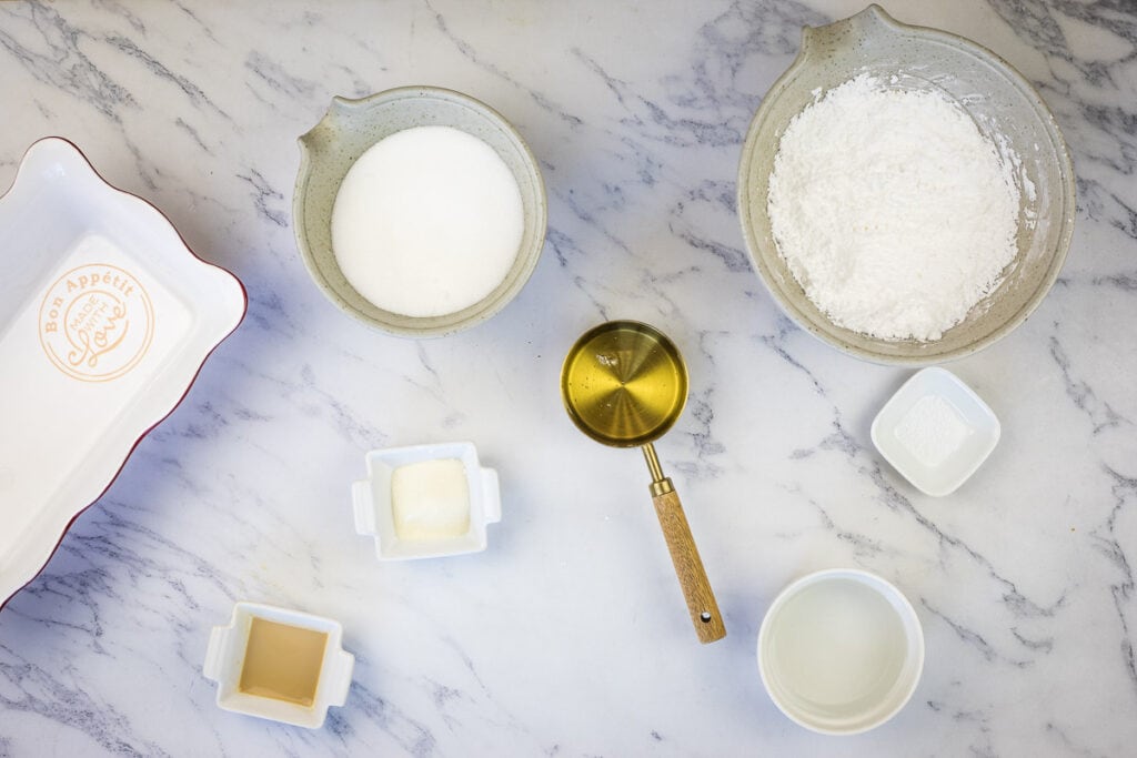 Sugar, flour, eggs and other ingredients on a marble counter.